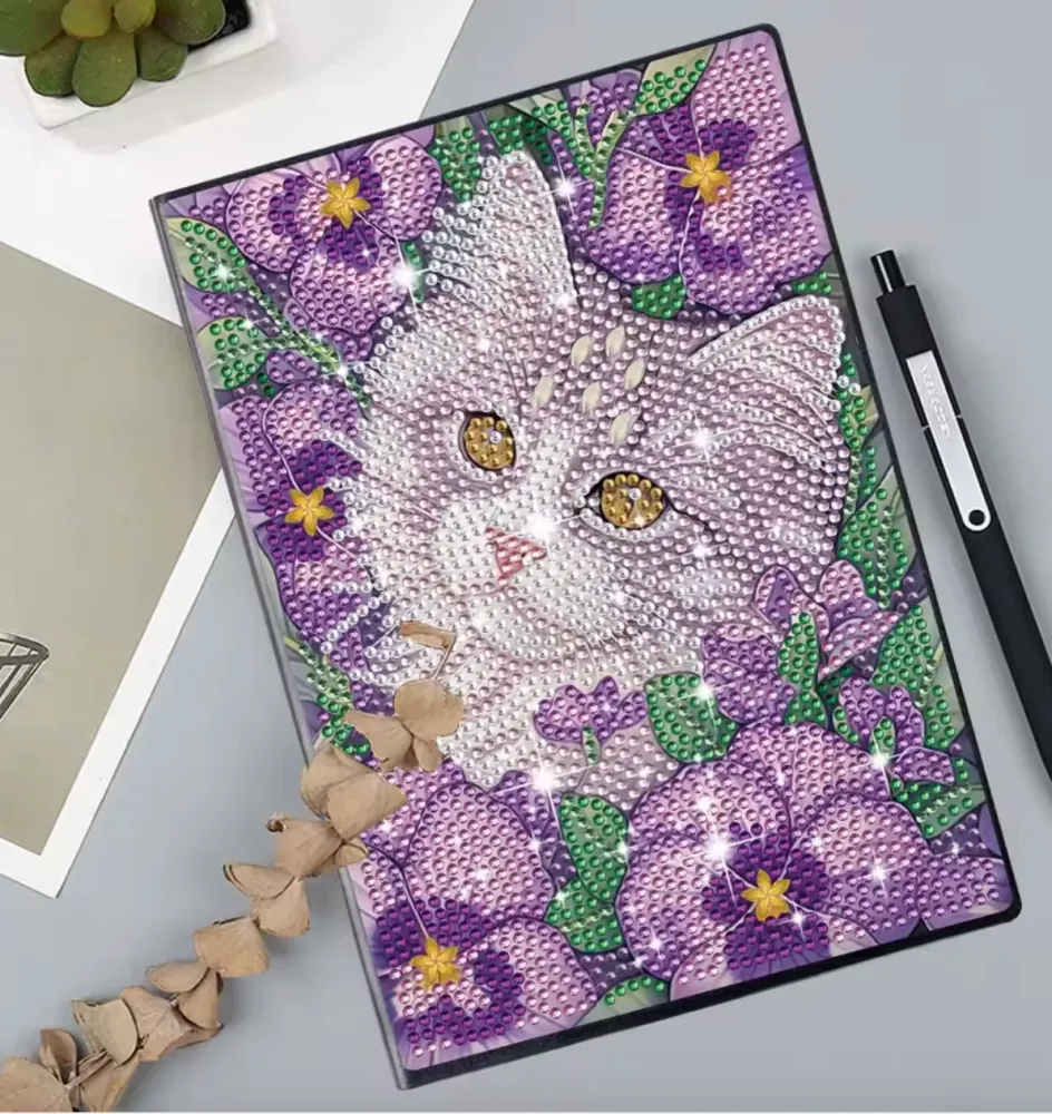 Notesbog med en kat omgivet af lilla blomster