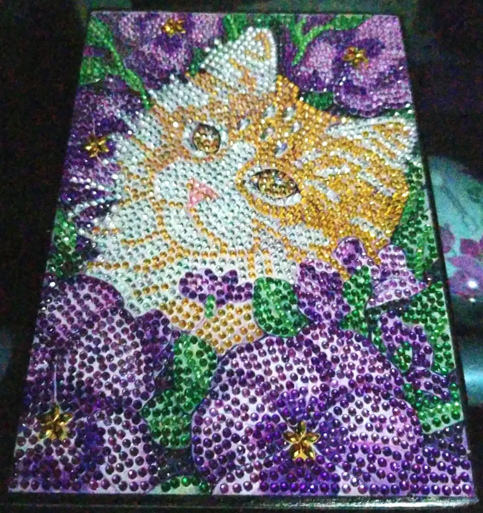 Notesbog med en kat omgivet af lilla blomster